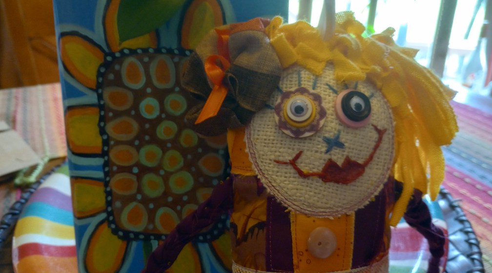 Close-up of a handmade Scrappy Doll by Kanda Kay — a burlap face with embroidered features, button eyes, and yarn hair